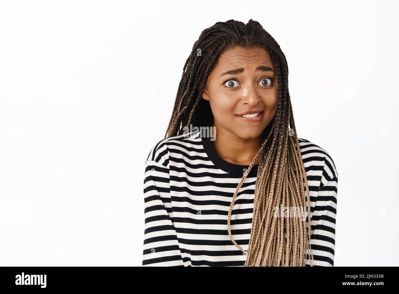 Portrait of excited african american woman yearning, looking with desire, smiling and biting lip from temptation, standing over white background Stock Photo