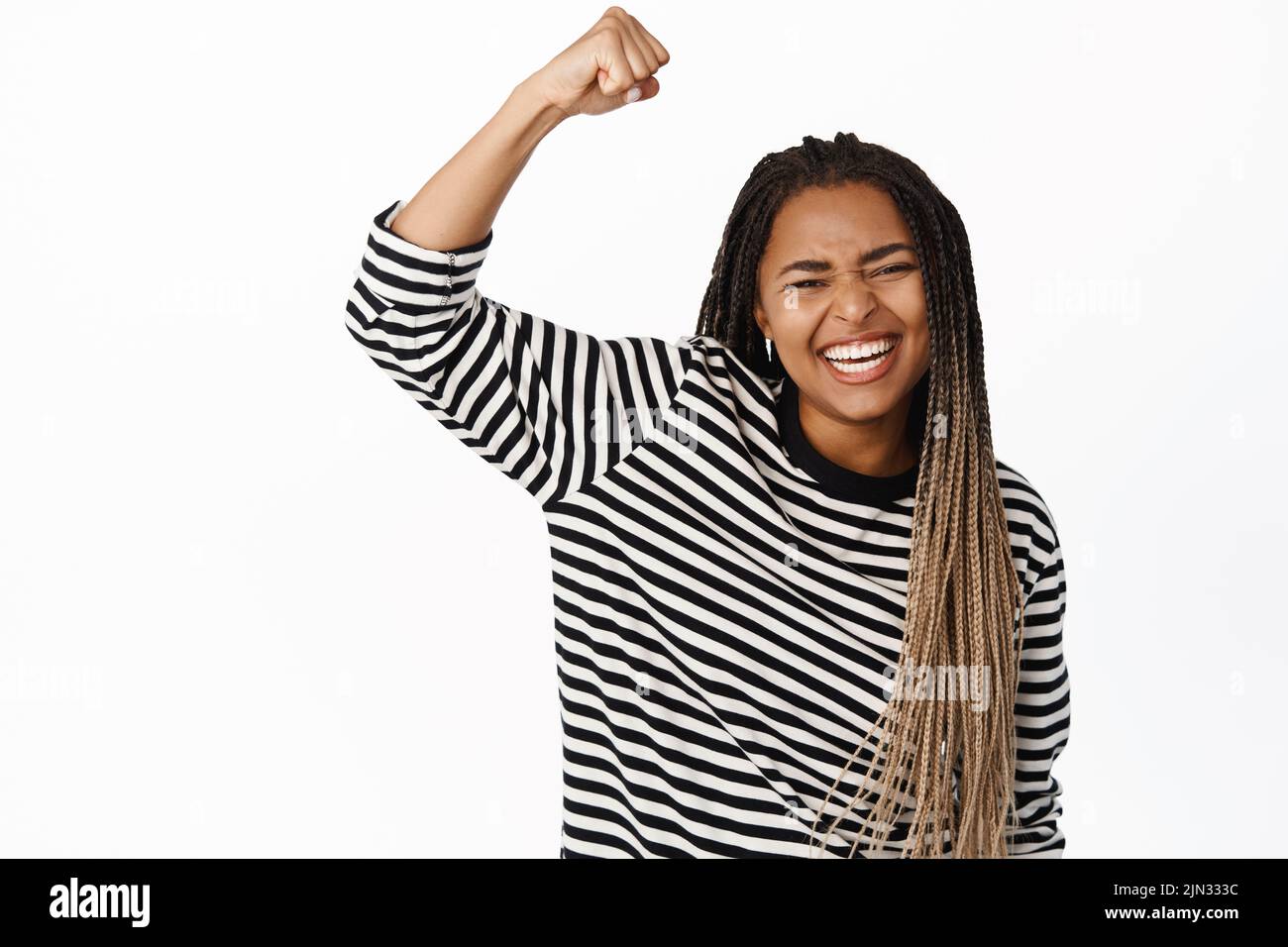 Excited black girl raising fist up, protesting, female activist chanting and rooting, celebrating victory, supporting team, standing over white Stock Photo