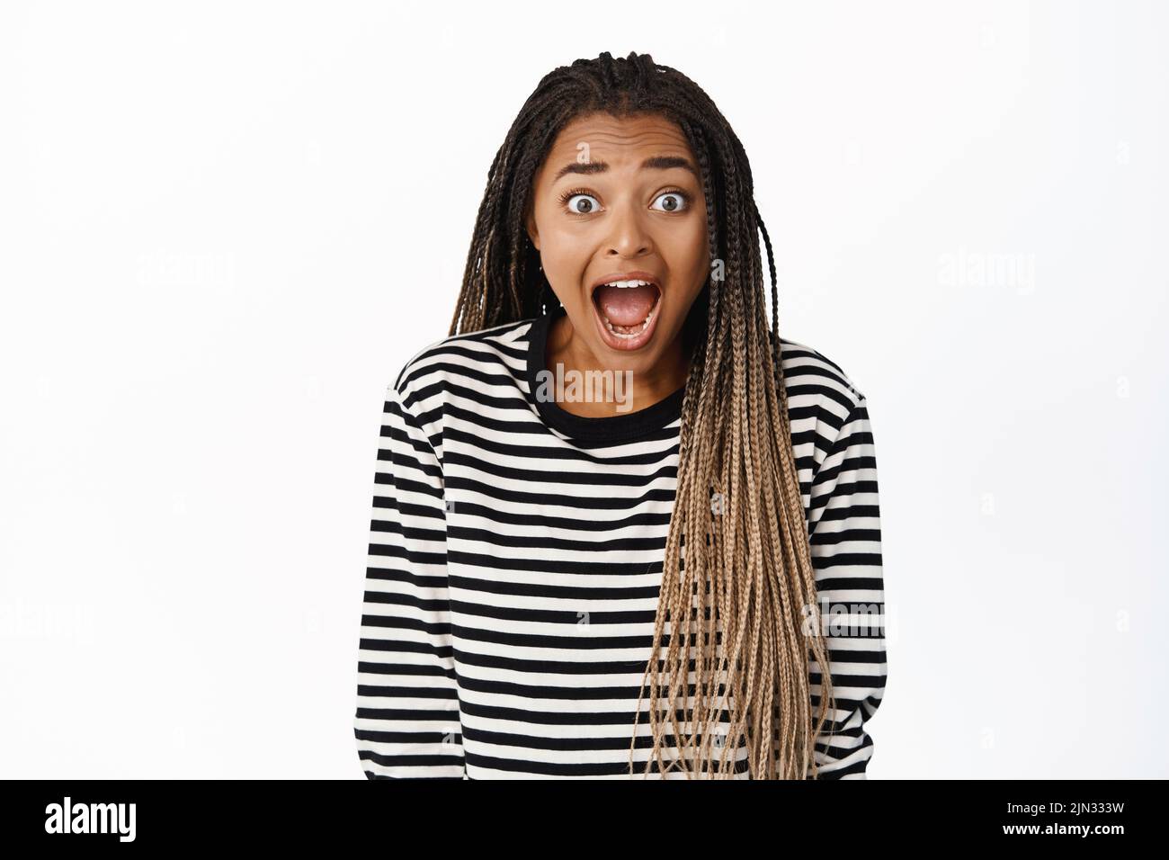 Image of excited black girl staring impressed at camera, checking out big promo sale, screaming of amazement and joy, look with awe and disbelief Stock Photo