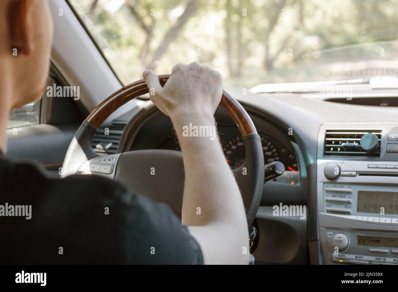 A man driving a car, rear view from the passenger compartment. Safe driving. Stock Photo