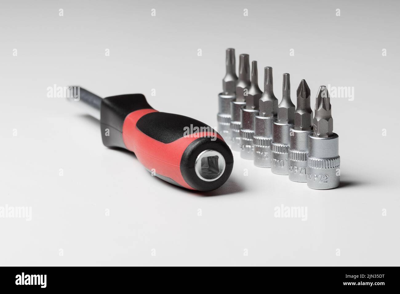 Screwdriver with attachments on the table on a white background. A set