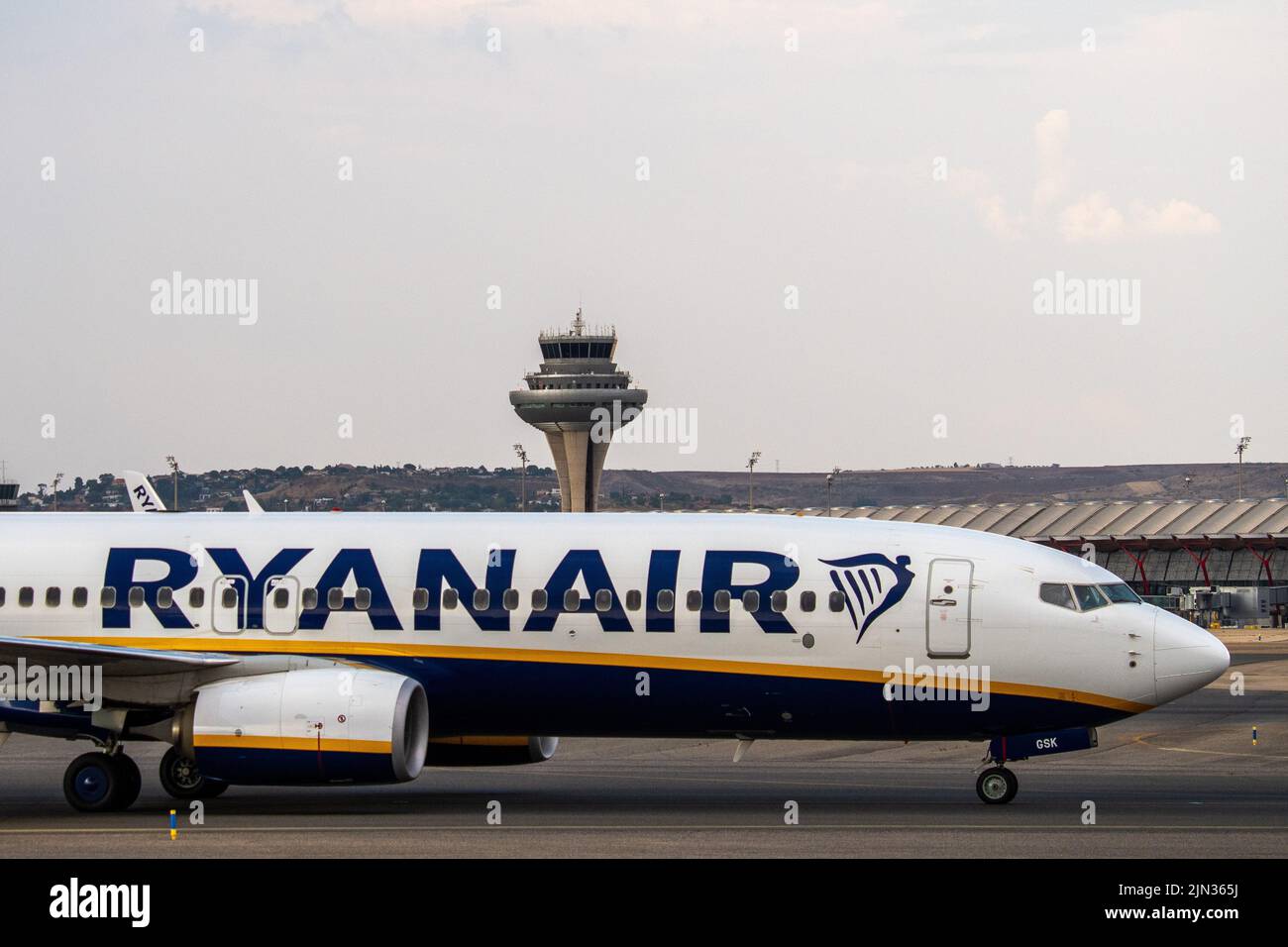 A Ryanair airplane in seen on the runway at Adolfo Suarez Madrid Barajas Airport passing by the air traffic control tower. Stock Photo