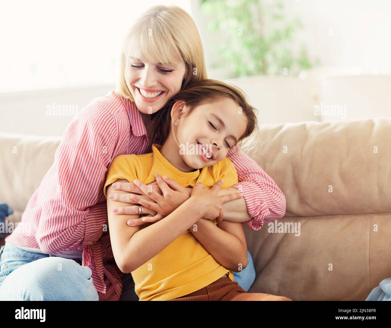 child mother family parent home woman happy daughter kid hug hugging together childhood girl mom love Stock Photo