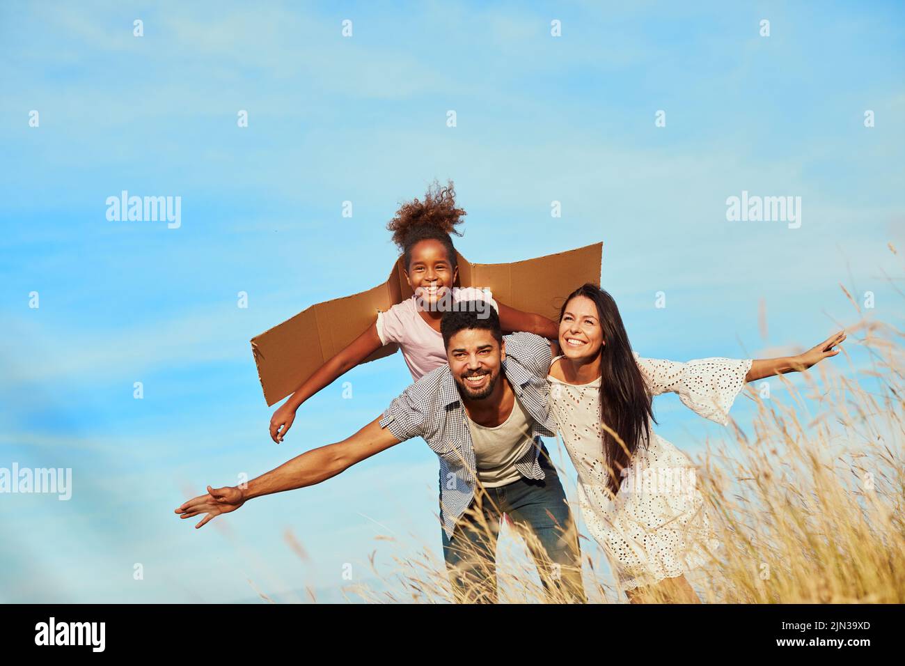 child daughter family happy mother father piggyback fun together girl cheerful field outdoor natur summer Stock Photo