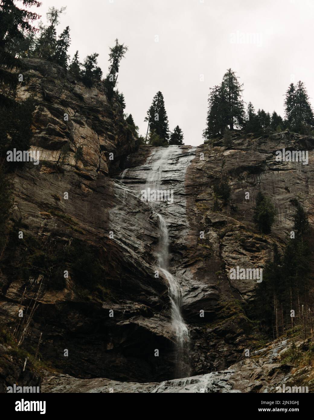 A beautiful waterfall on a rocky mountain with trees on the top Stock ...