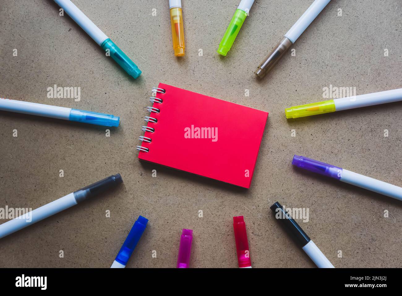 Notepad for notes with red sheets. Blank space for notes. Mocap. On warm ochre kraft background. Small spring-loaded notebook resting on table surroun Stock Photo
