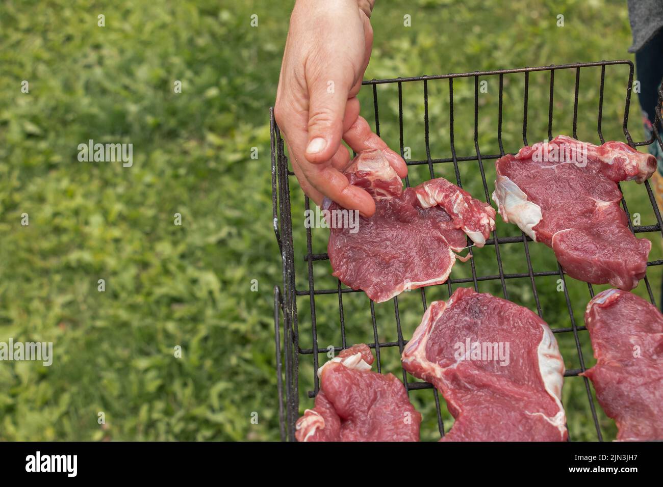 Women's hands prepare raw beef steaks for frying on the grill Stock