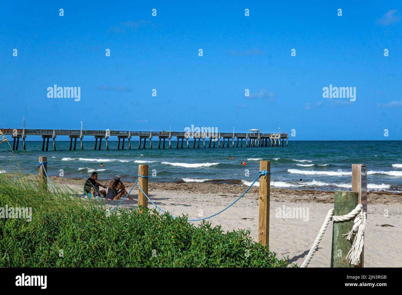 Dania Beach, FL - USA July 27, 2022 Landscape view of Dania Beach Ocean Park Pier and swimmers on the Atlantic Ocean  in southern Florida. Stock Photo