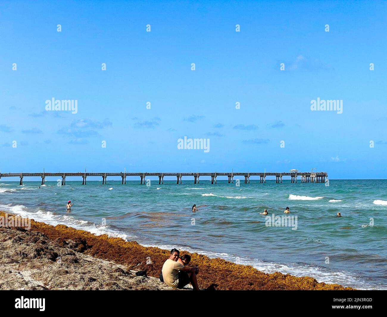 Dania Beach, FL - USA July 27, 2022 Landscape view of Dania Beach Ocean Park Pier and swimmers on the Atlantic Ocean  in southern Florida. Stock Photo