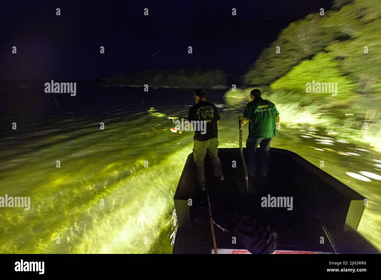 An alligator hunting guide and his client are silhouetted by underwater