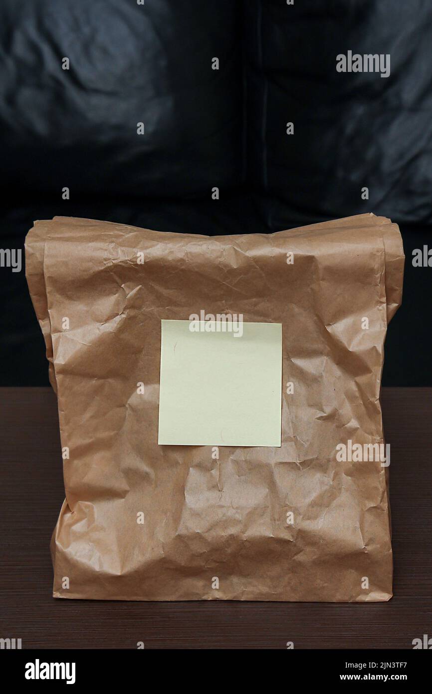 Brown paper bag used for food delivery standing on interior table Stock