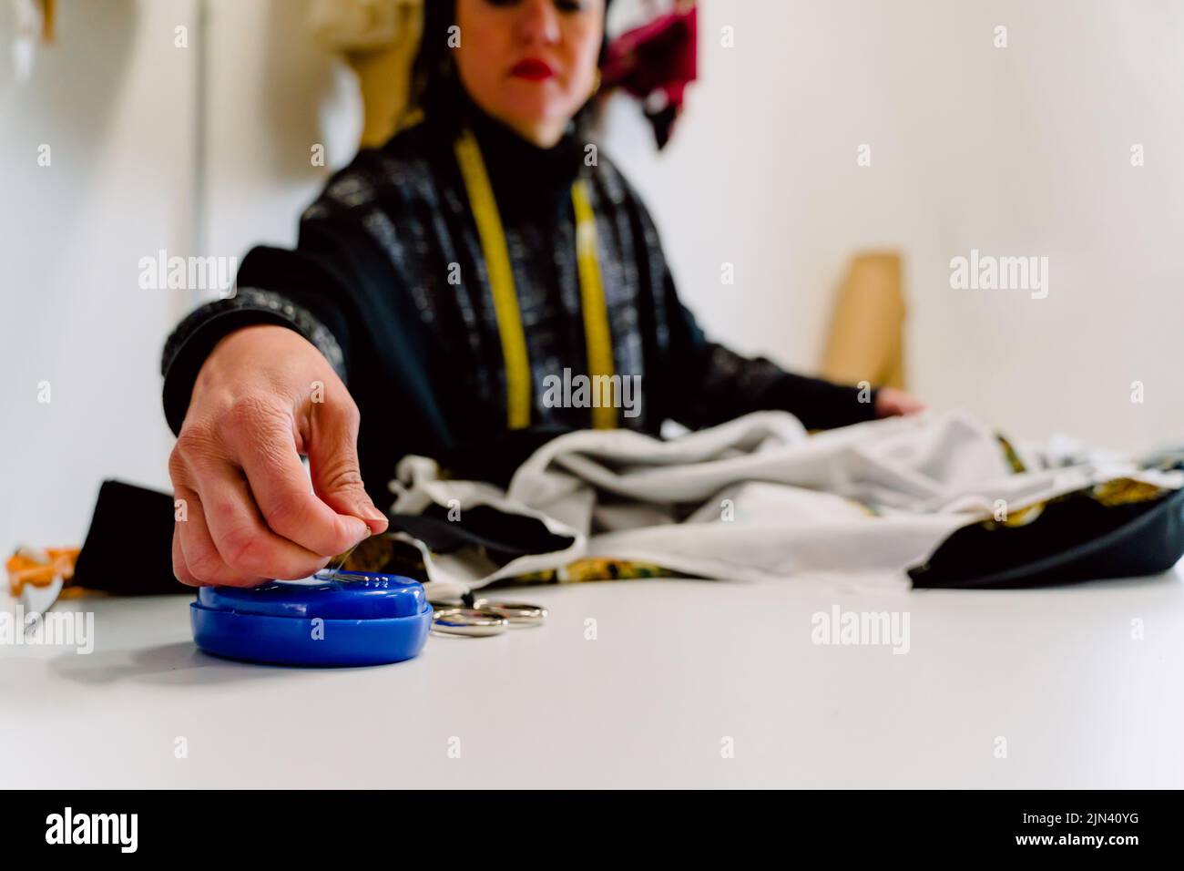 Dressmaker woman picking up needles to design clothes Stock Photo Alamy