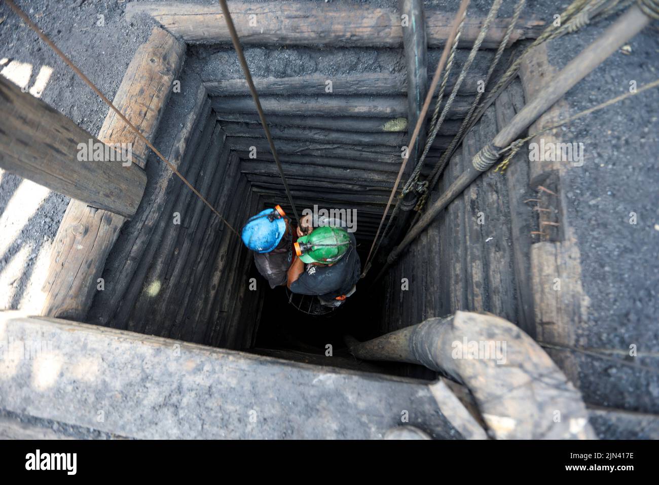 Miners descend into an artisanal coal mine, or 'pocito' (little hole), known for their rudimentary and often dangerous mining techniques, in Sabinas, Coahuila state, Mexico, August 8, 2022. REUTERS/Luis Cortes Stock Photo
