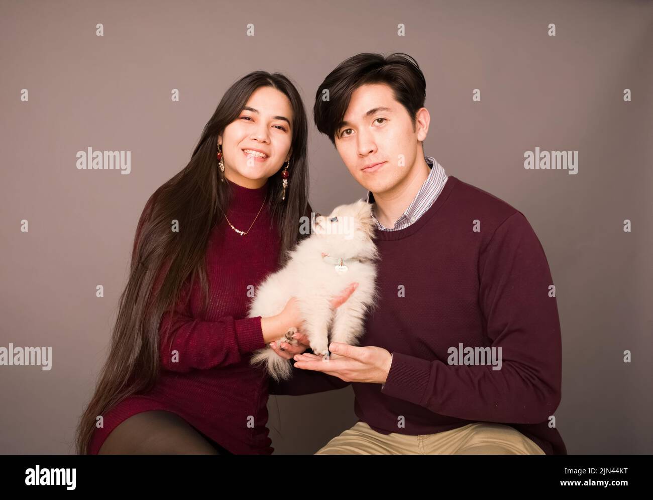 Attractive young biracial couple posing with purebred white Pomeranian puppy Stock Photo