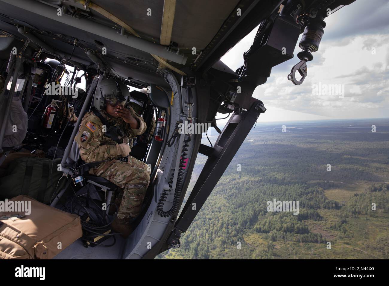 A US Army soldier assigned to the 1-230th Assault Helicopter Battalion, Tennessee Army National Guard, communicates with his UH-60 Blackhawk flight crew during Pre-accident Plan Rehearsal for Northern Strike 22 above Camp Grayling, Mich., Aug. 6, 2022. Northern Strike is designed to challenge 7,400 service members with multiple forms of training that advance interoperability across multicomponent, multinational and interagency partners. Stock Photo