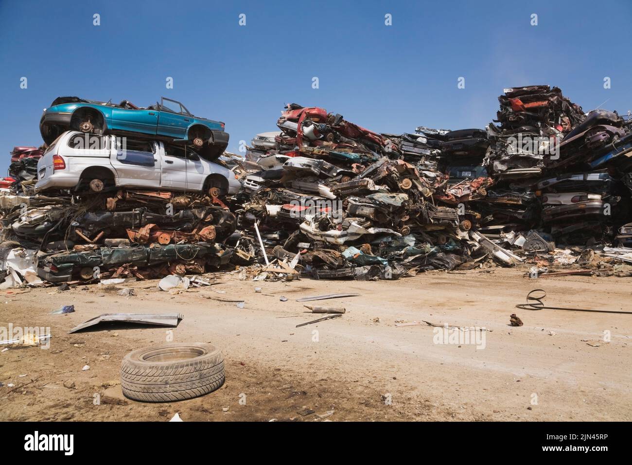 Stacked and crushed discarded automobiles at scrap metal recycling yard ...