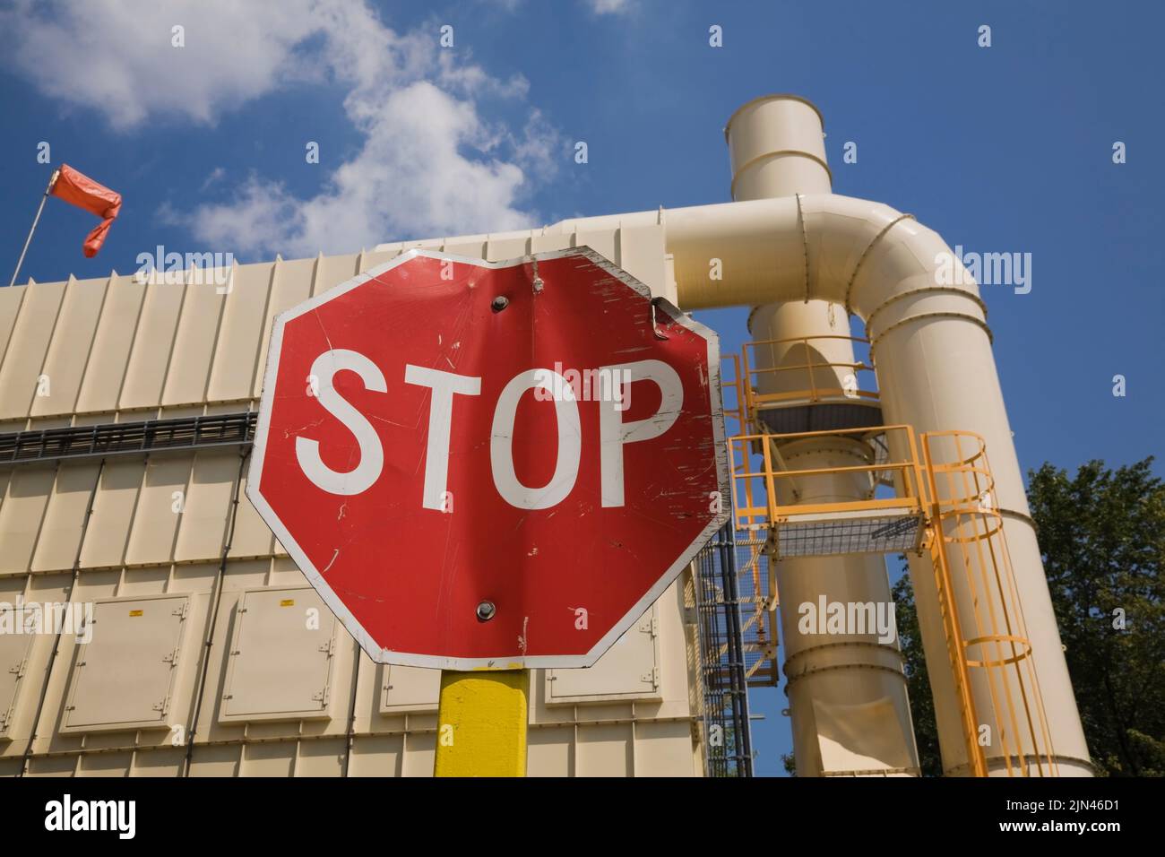 Stop sign and smoke stack at industrial recycling facility Stock Photo