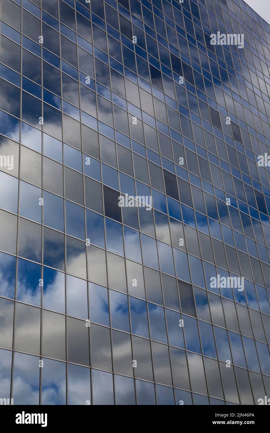 Blue sky and clouds reflected in modern glass and steel office tower ...