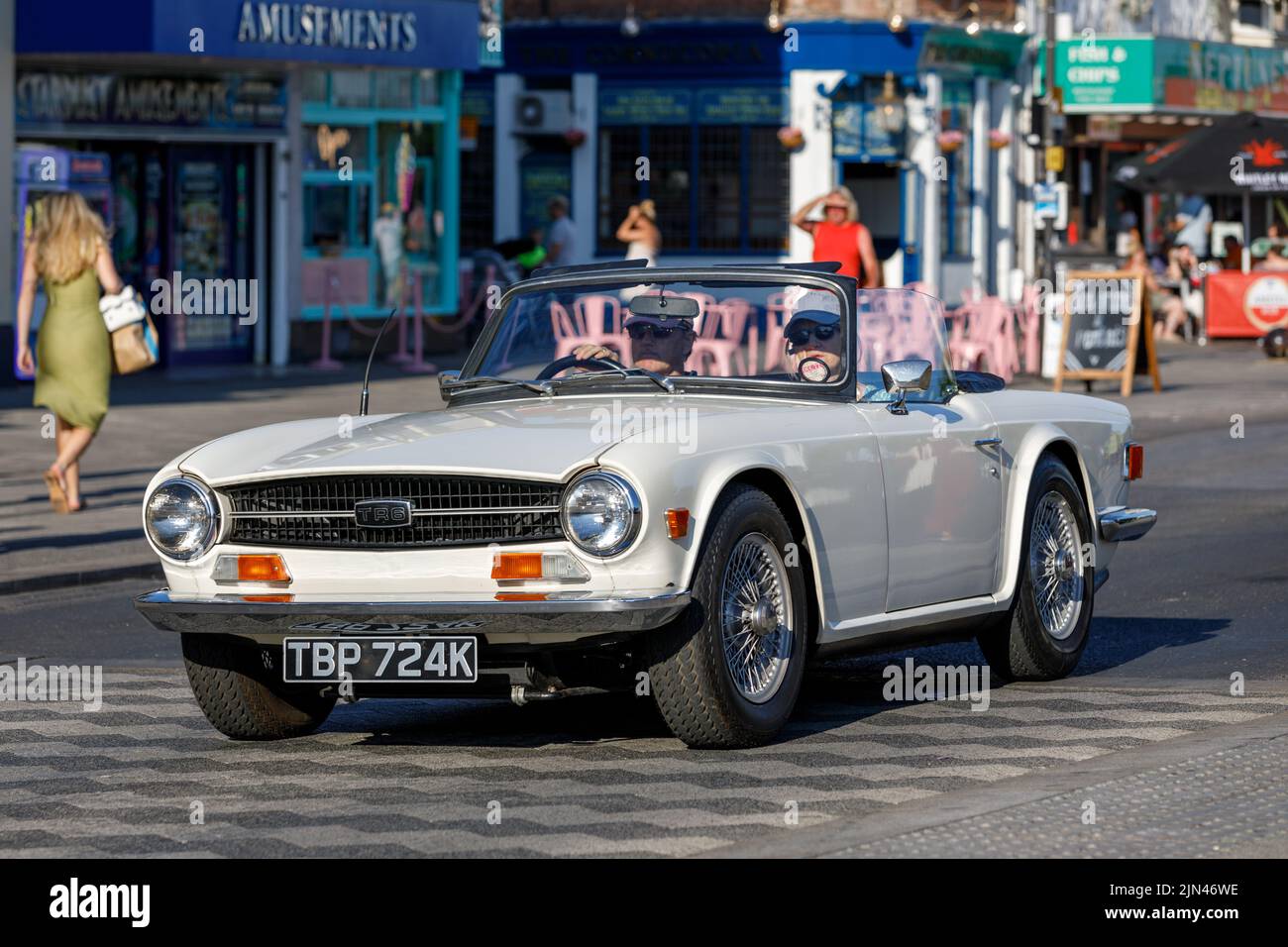 A white Triumph TR6 convertible with hood down being driven along Marine Parade on the English seaside in Essex during the heatwave of 2022 Stock Photo