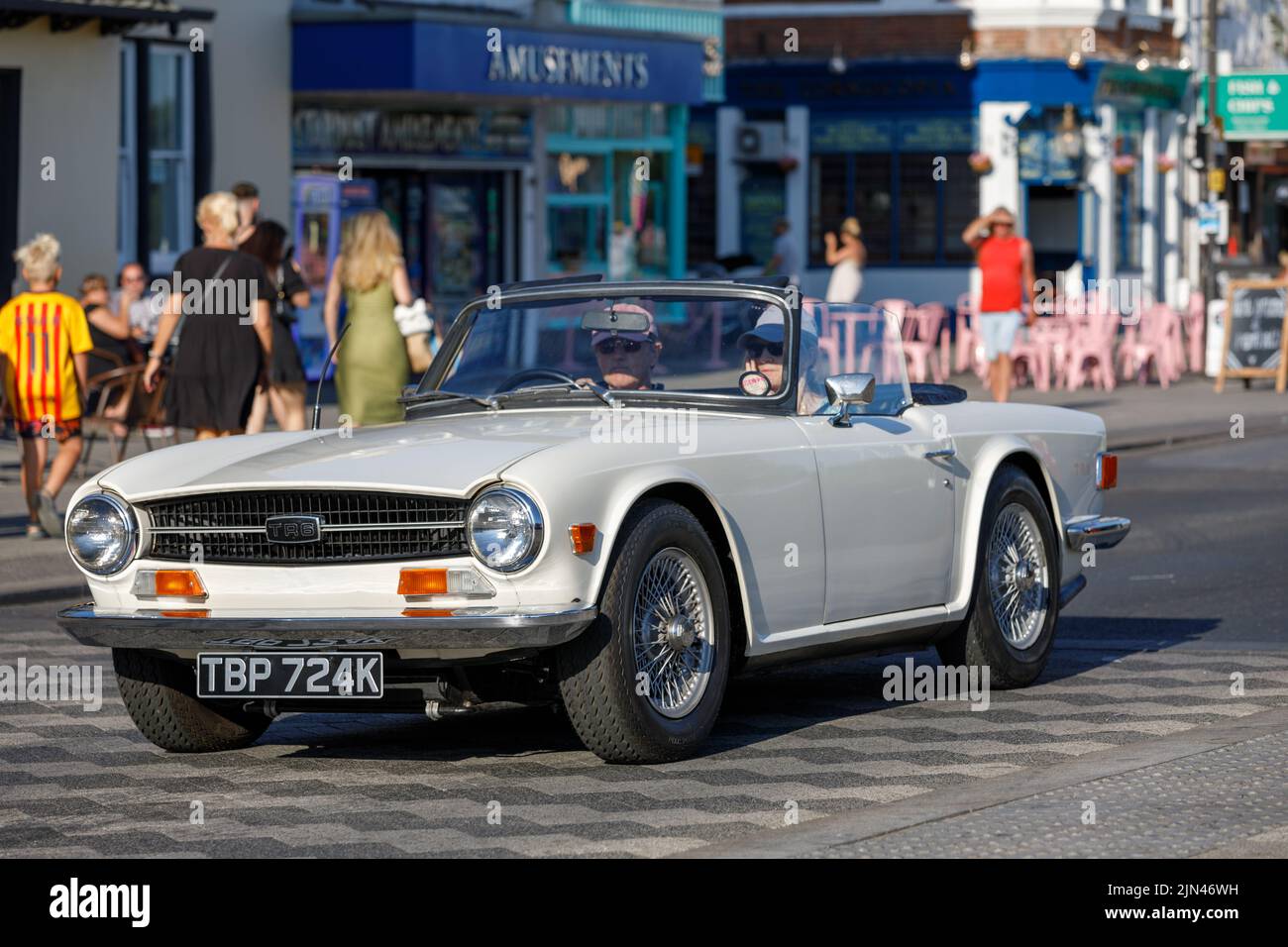 A white Triumph TR6 convertible with hood down being driven along Marine Parade on the English seaside in Essex during the heatwave of 2022 Stock Photo