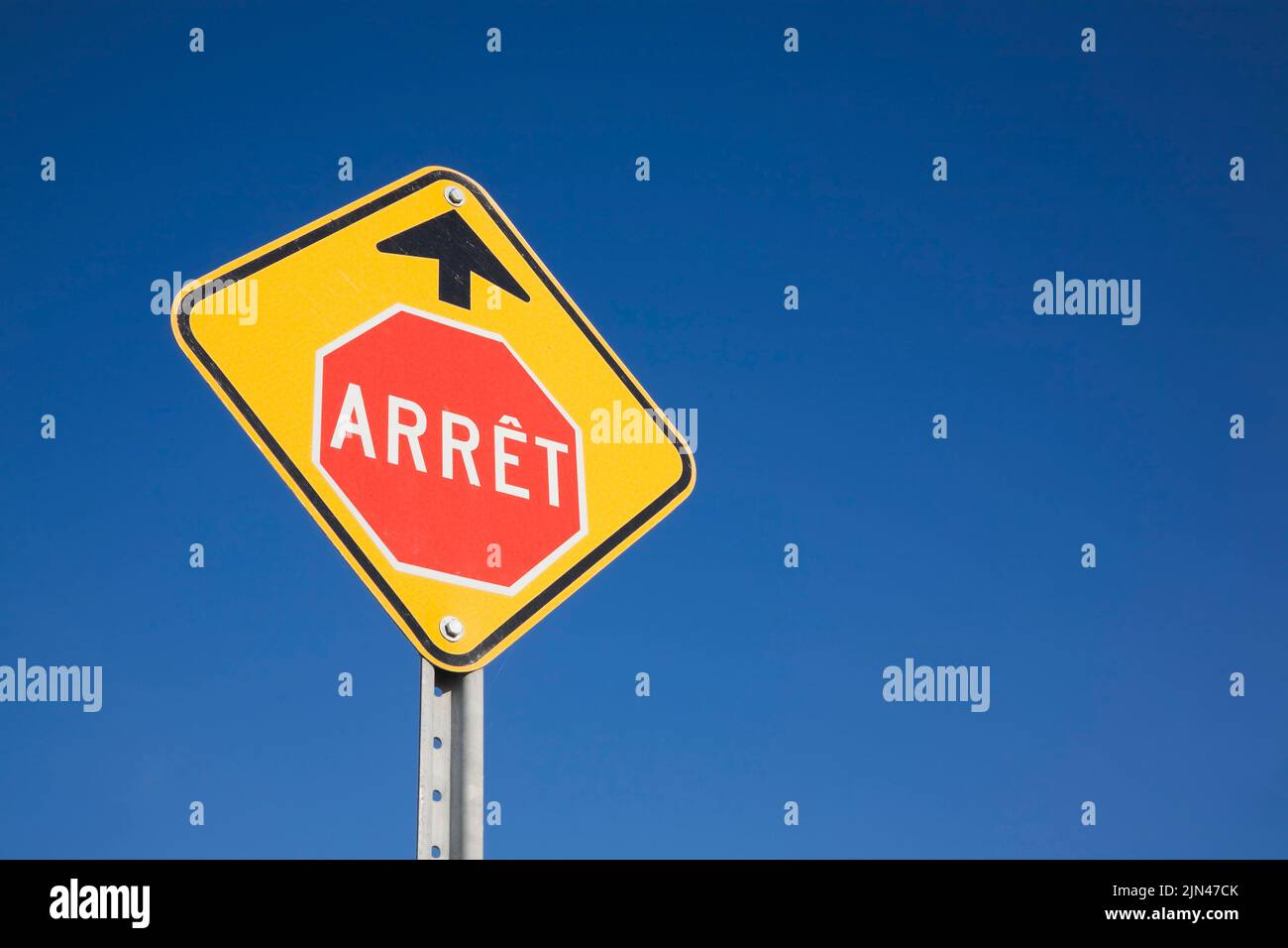 French language stop sign warning ahead sign against a blue sky background, Quebec, Canada Stock Photo
