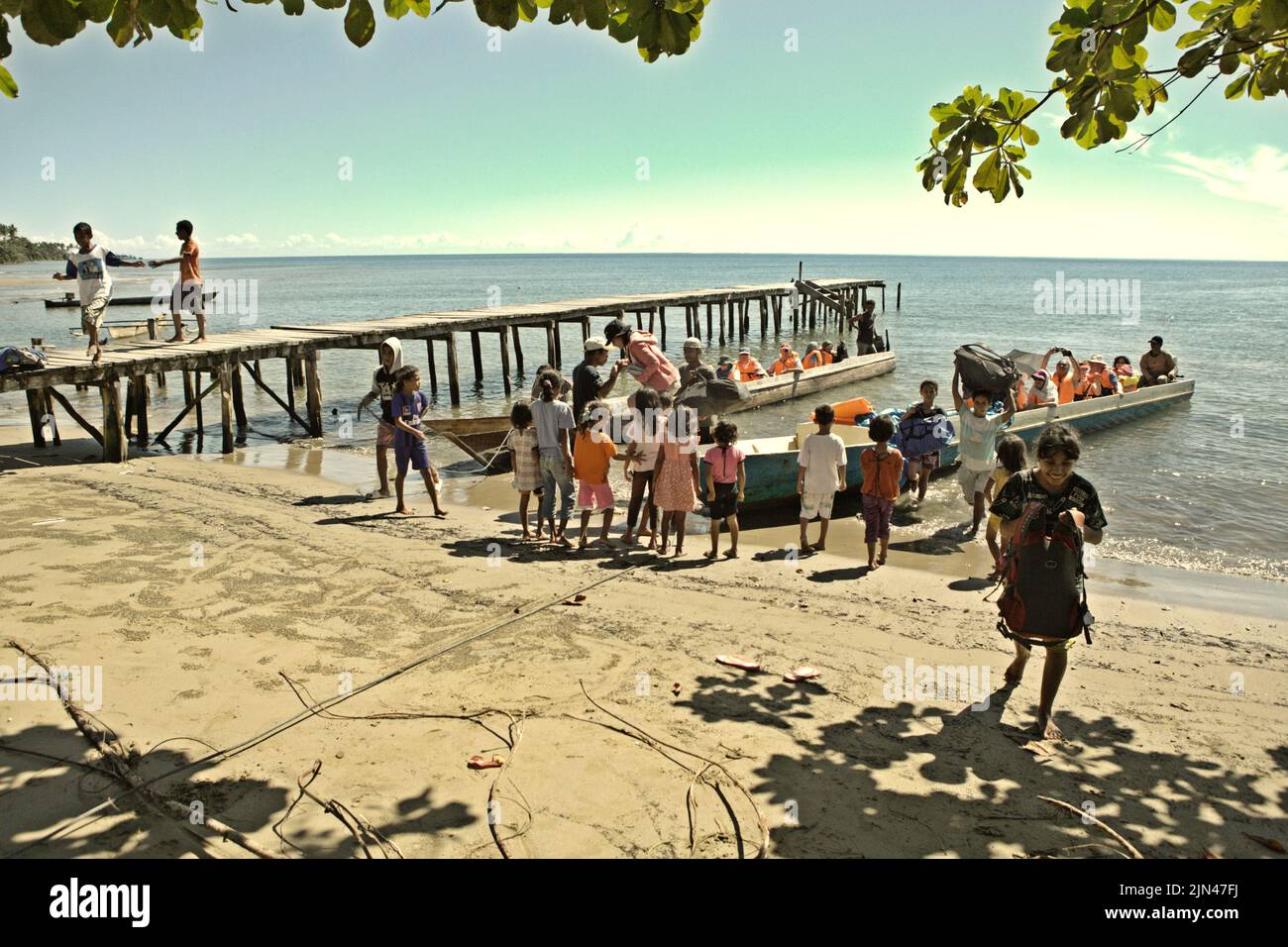 Villagers welcoming a boat carrying tourists to help with the baggages on the beach of Horale village in Seram Utara Barat, Maluku Tengah, Maluku, Indonesia. Stock Photo
