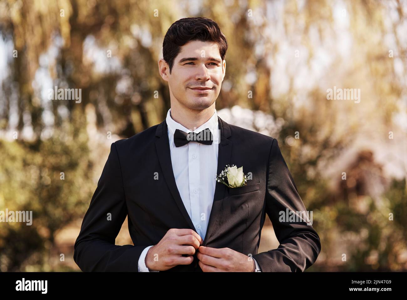 Preparing to say his I dos. a handsome young bridegroom adjusting his suit while preparing for his wedding outdoors. Stock Photo
