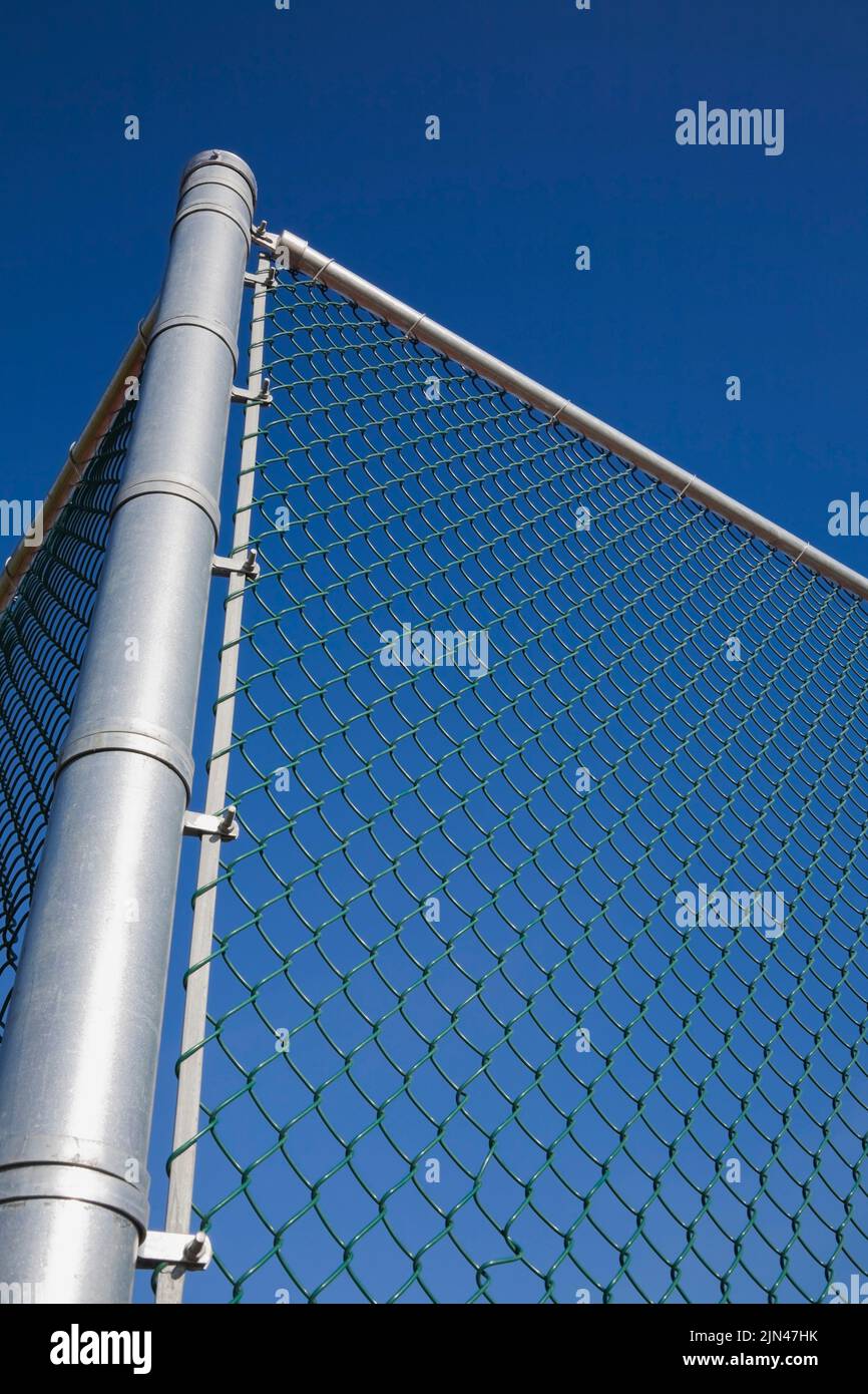 New chain link security fence with metal post against a blue sky, Quebec, Canada Stock Photo