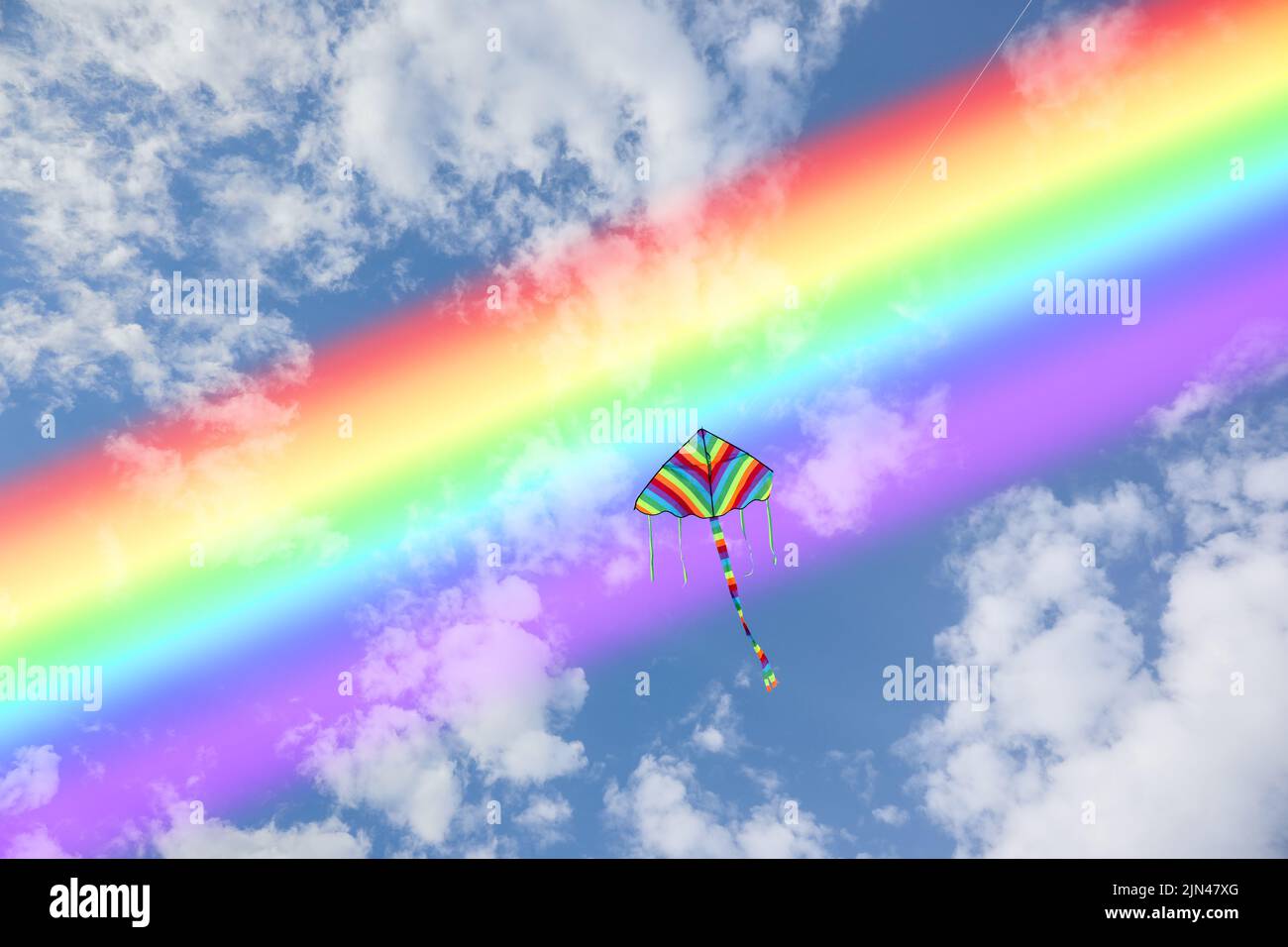 Colorful kite flying in blue sky with rainbow Stock Photo Alamy
