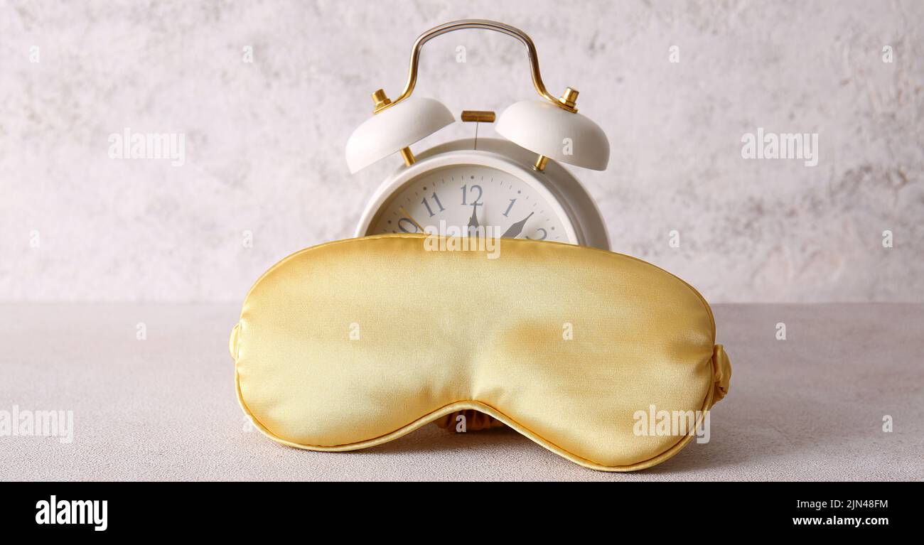 Sleep mask and alarm clock on light background Stock Photo Alamy