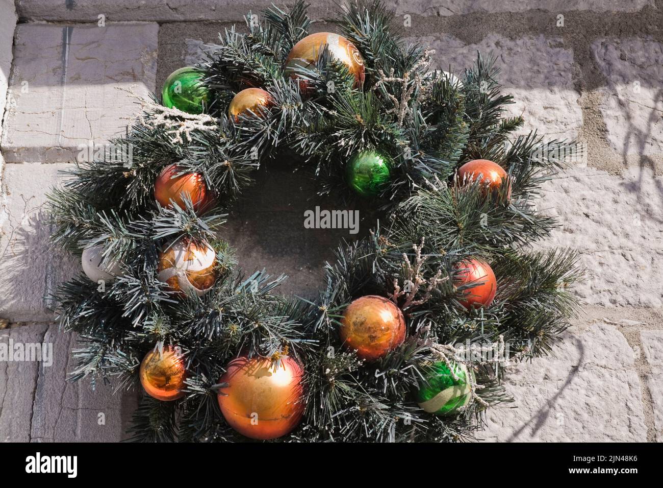 Christmas wreath decorated with ornaments on old stone wall, Quebec, Canada Stock Photo
