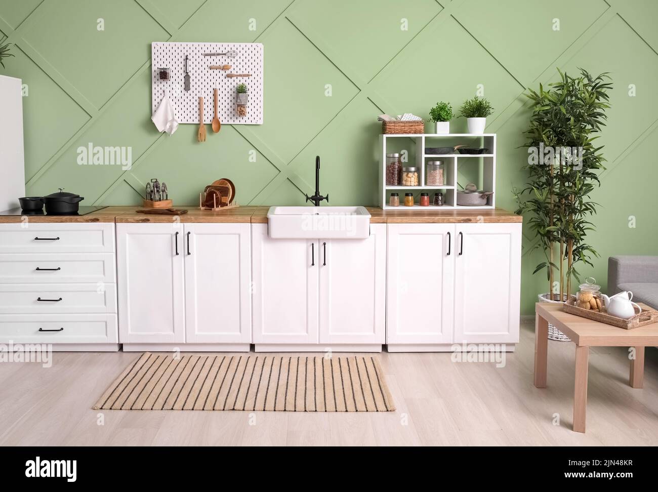 Interior of stylish kitchen with white counters, pegboard and shelving
