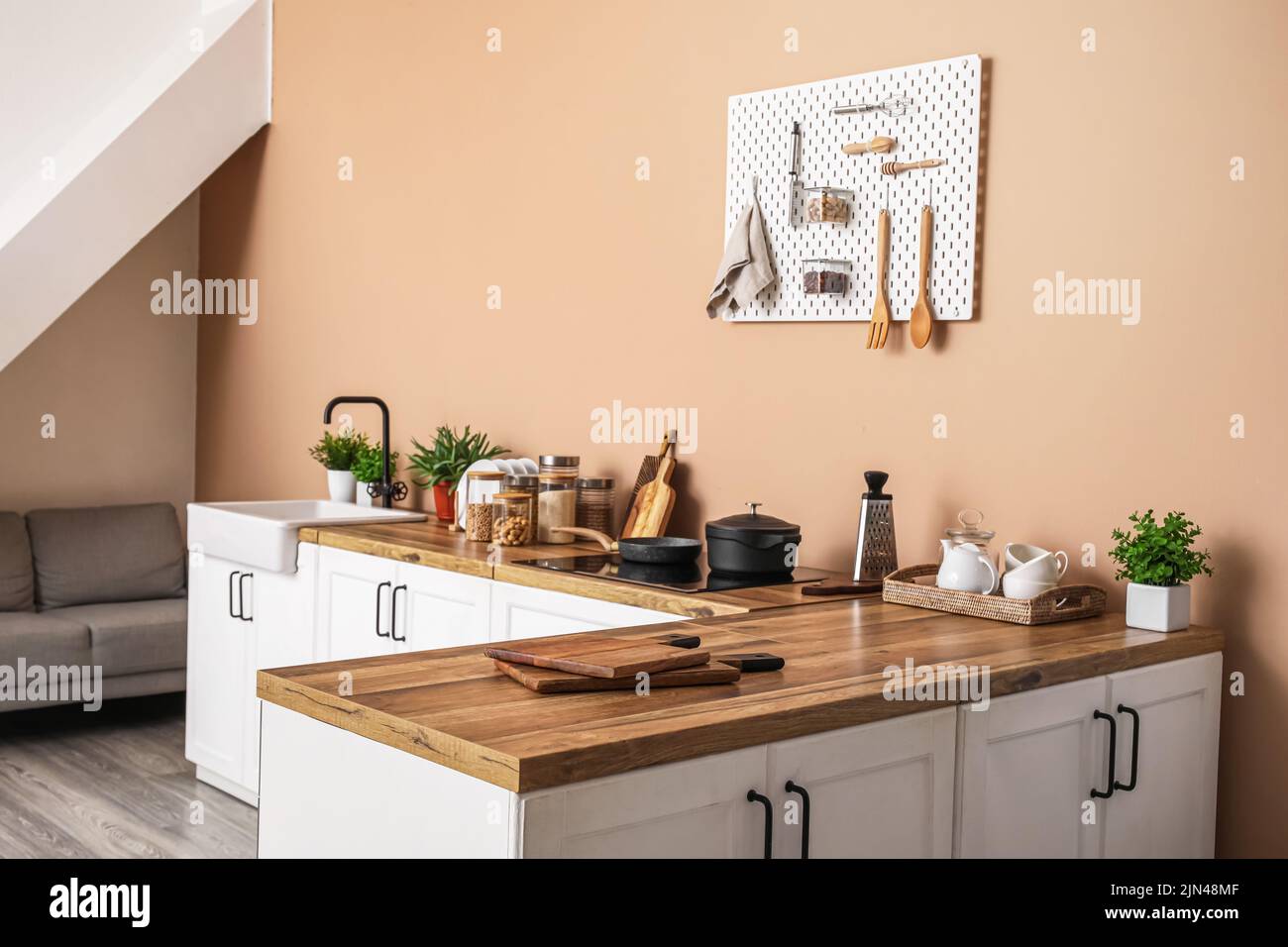 Interior of stylish kitchen with white counters, utensils and pegboard ...