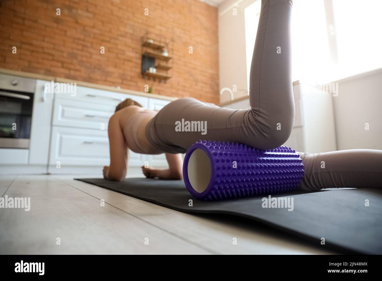 Young woman training with foam roller in kitchen Stock Photo - Alamy