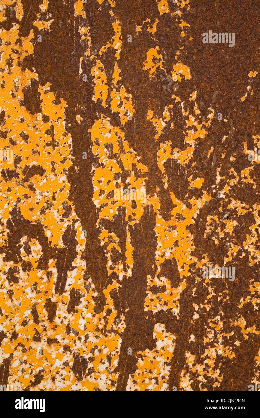 Close-up of peeling yellow paint and rust patterns on a ferous metal surface, Quebec, Canada Stock Photo