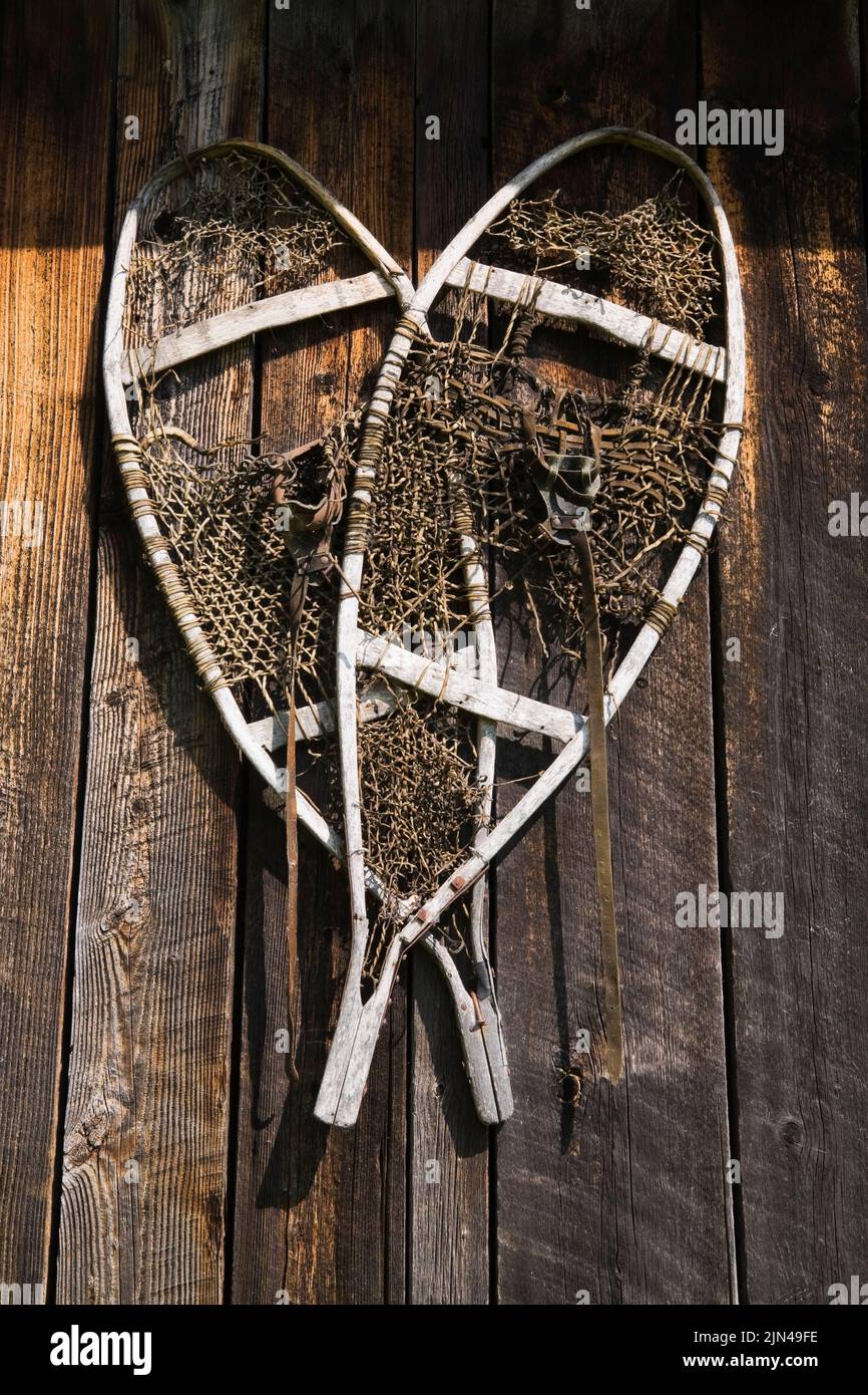 Pair of old wooden and lace snowshoes hanging on side of an old storage shed. Stock Photo
