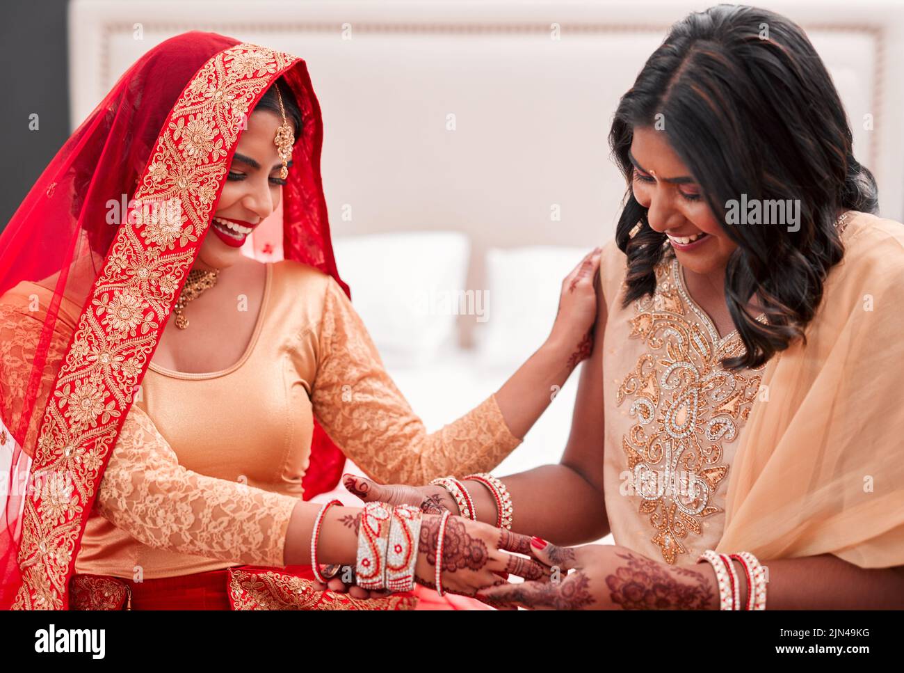 These are just perfect. a young woman getting her bracelets put on by her bridesmaid on her wedding day. Stock Photo