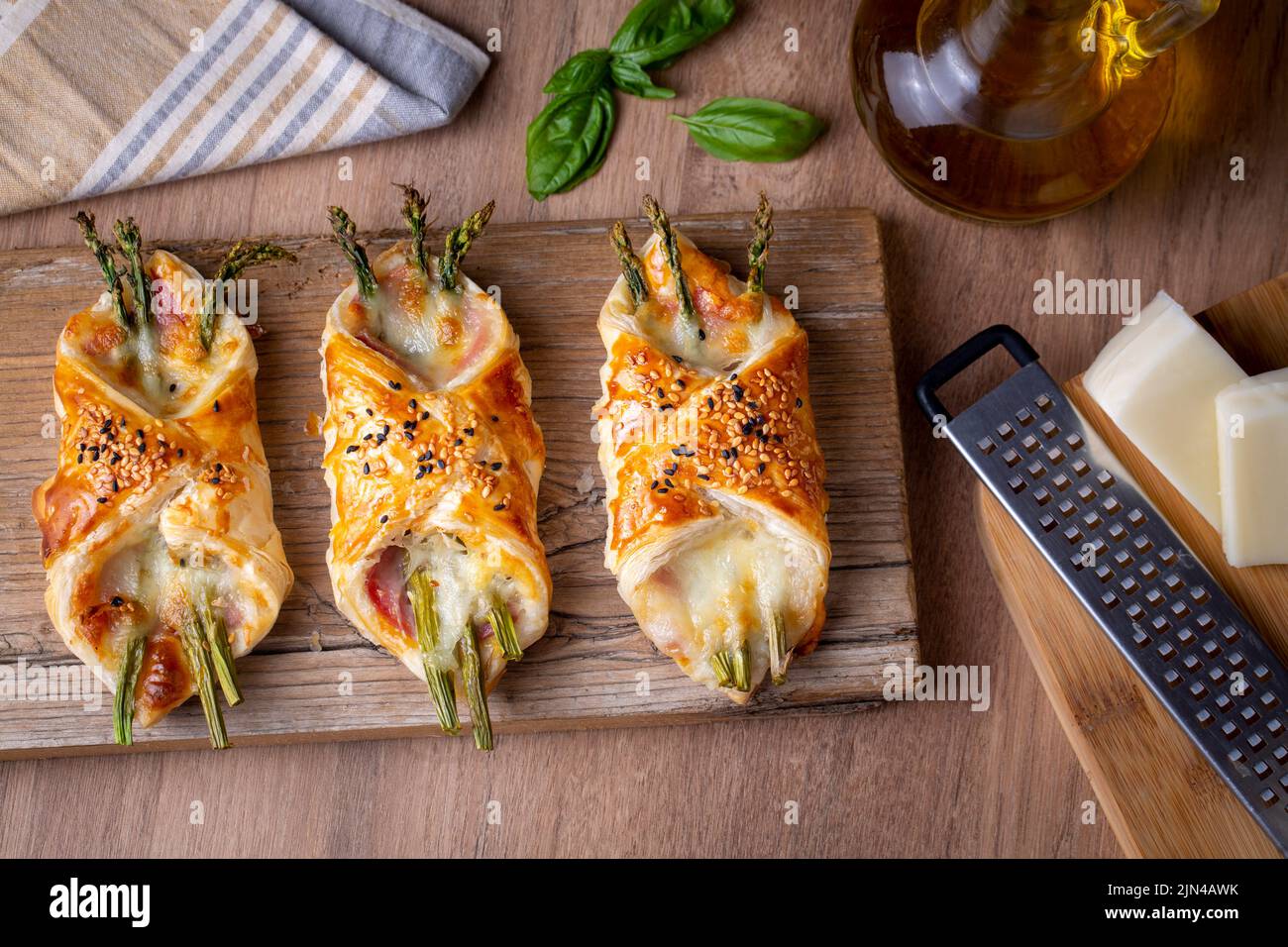 Baked green asparagus with ham and cheese in puff pastry sprinkled with