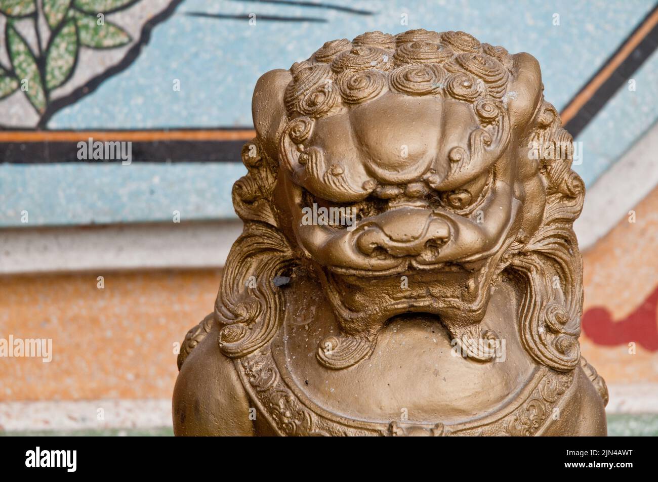 Strong and majestic golden dark bronze Asian Chinese lion metallic statue in a temple Stock Photo