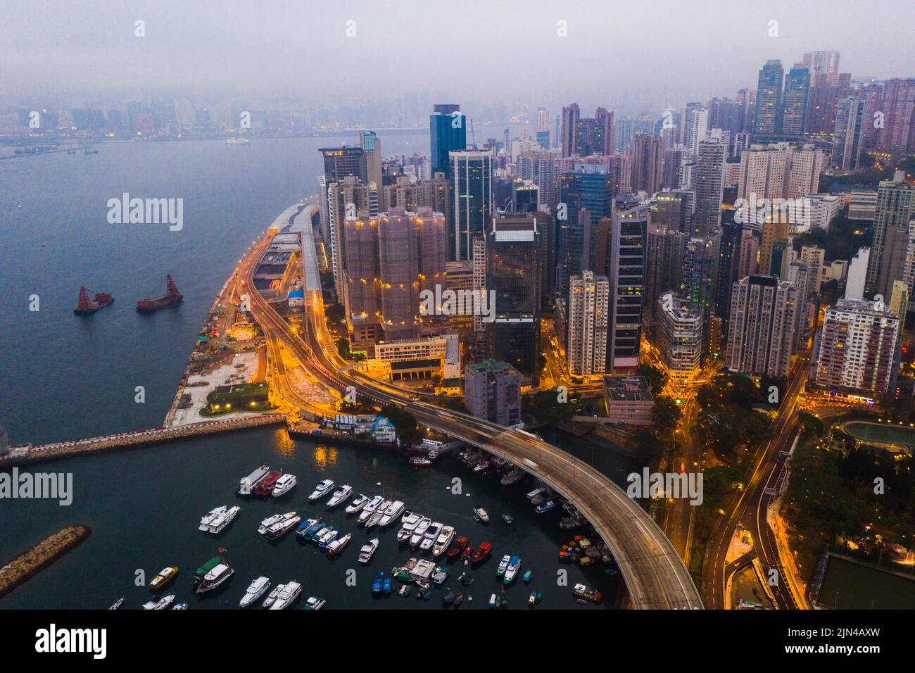 The city comes to life after the sun sets. Aerial shot of skyscrapers, office blocks and other commercial buildings in a busy coastal city. Stock Photo