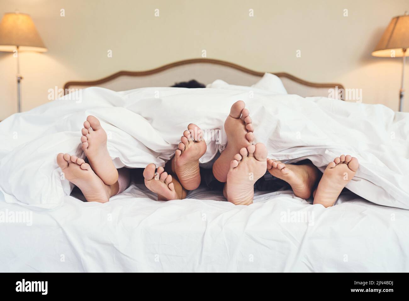 Carefree days are simply the best. a familys feet peeking out from a blanket at home. Stock Photo