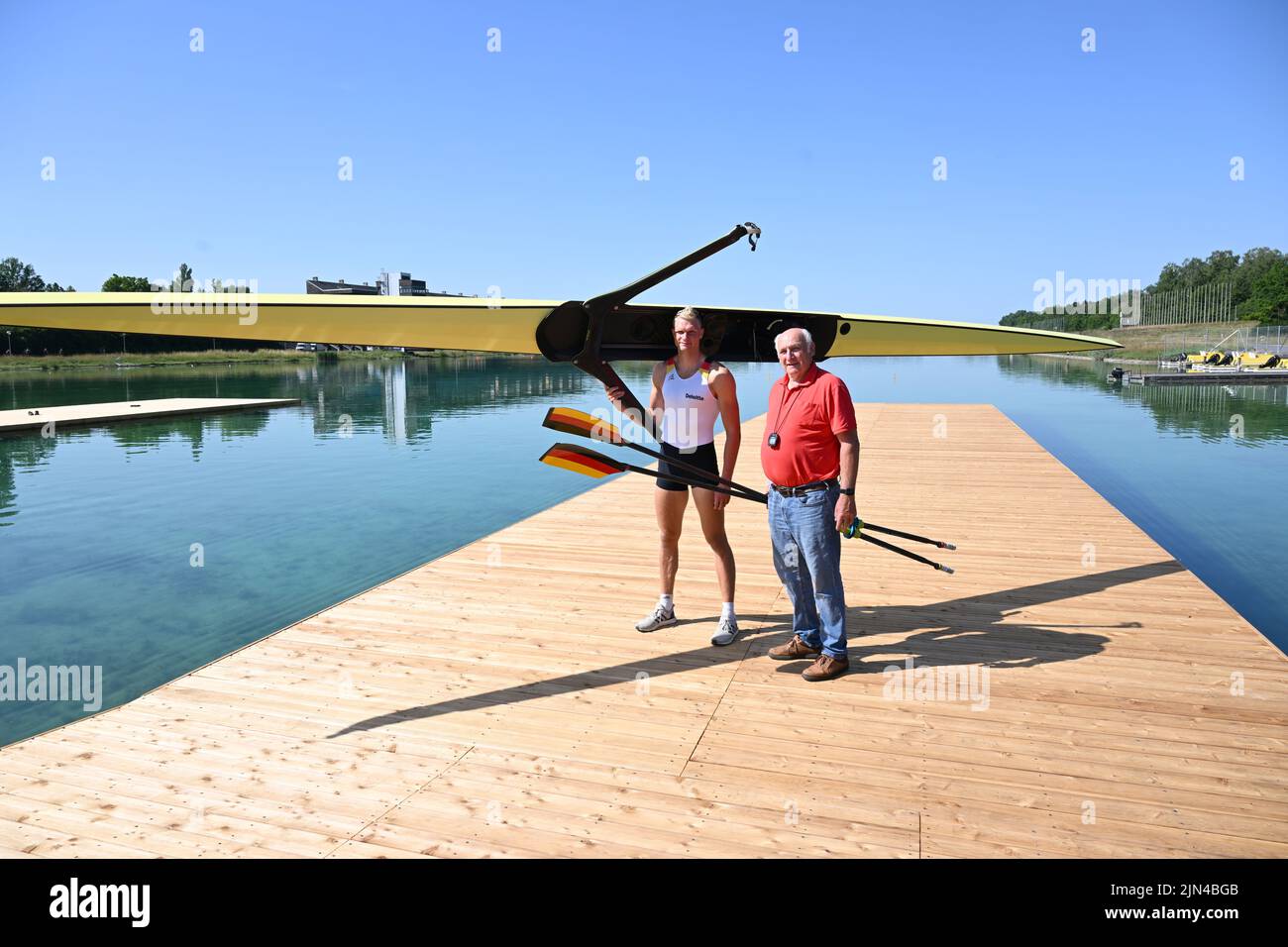 PRODUCTION - 27 June 2022, Bavaria, Oberschleißheim: World and European rowing champion Oliver Zeidler (l) and 1972 Olympic rowing champion Hans-Johann Färber stand at the Oberschleißheim rowing regatta course. Zeidler is the grandson of Hans-Johann Färber. (to dpa 'Once the grandfather, now the grandson: A rowing gold 'dahoam' should her') Photo: Felix Hörhager/dpa Stock Photo