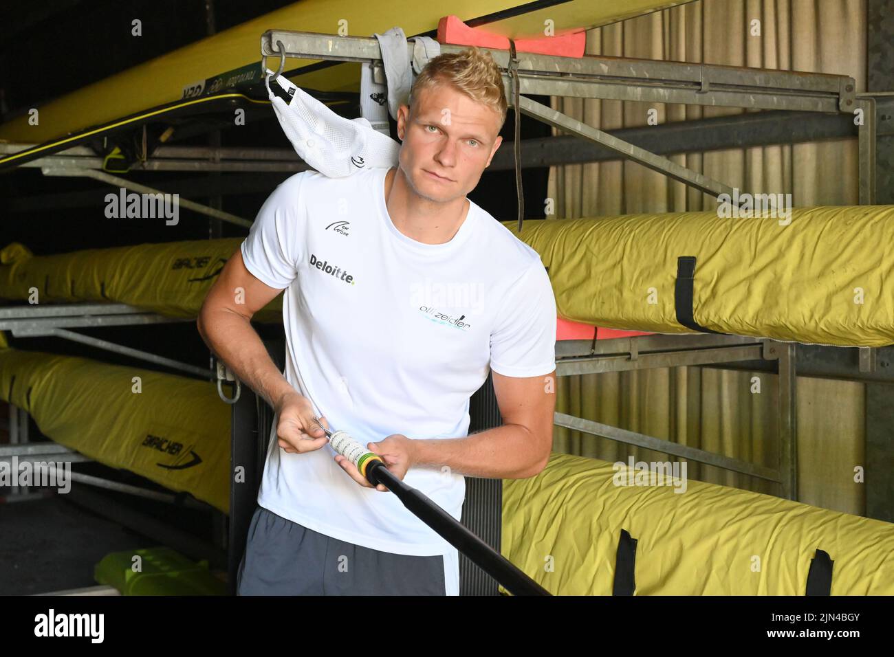 PRODUCTION - 27 June 2022, Bavaria, Oberschleißheim: World and European rowing champion Oliver Zeidler stands in a boat hall at the Oberschleißheim rowing regatta course. As a child, European champion Oliver Zeidler thought it was 'cool' to see his grandfather in the Olympic book from Munich 1972. 50 years after his grandfather's rowing gold medal, the grandson is aiming for the title himself at the historic site. (to dpa 'Once the grandfather, now the grandson: A rowing gold 'dahoam' should her') Photo: Felix Hörhager/dpa Stock Photo