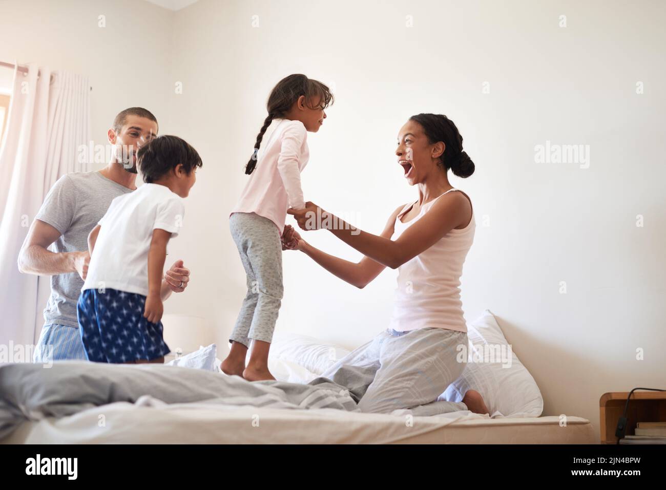 Family always comes first. a beautiful young family of four having fun and spending time together in their bedroom at home. Stock Photo