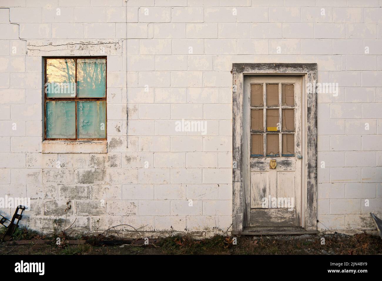 Dilapidated Cinder Block Building with Weathered Door and Window Stock Photo