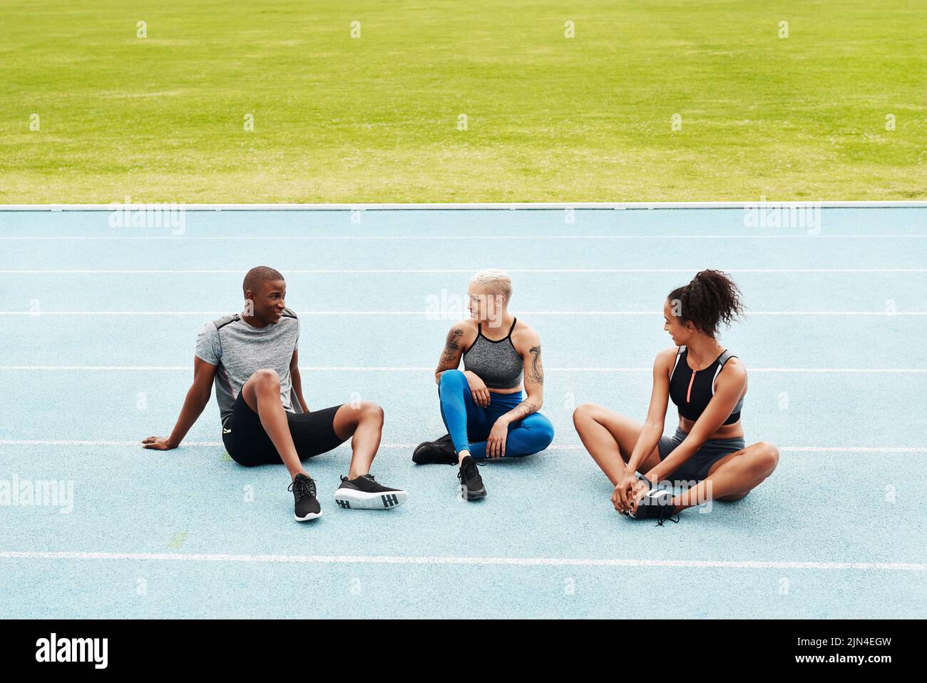 Relaxing after the race. Full length shot of a diverse group of athletes sitting together after a team training session on a running track. Stock Photo