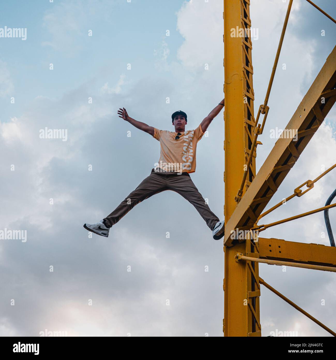 Latin young man posing on top of a yellow structure. Hispanic young man
