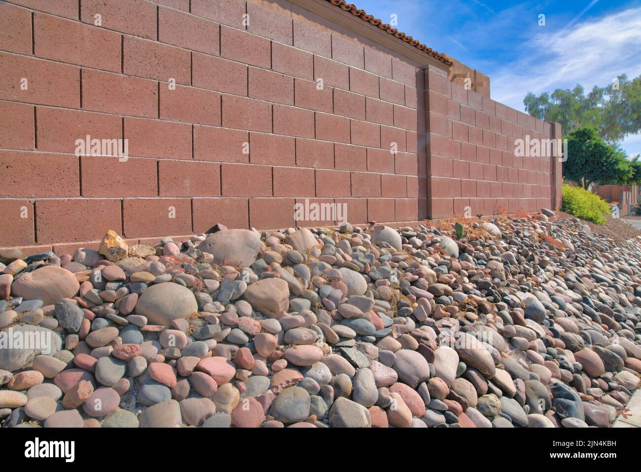 Rock wall on a slope below a brown concrete wall in Tucson, Arizona