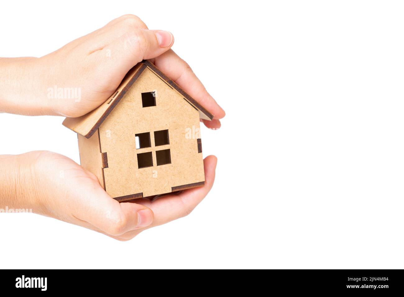 Holding a miniature wooden house model with both hands isolated on neutral background. Home insurance and care concept. Stock Photo