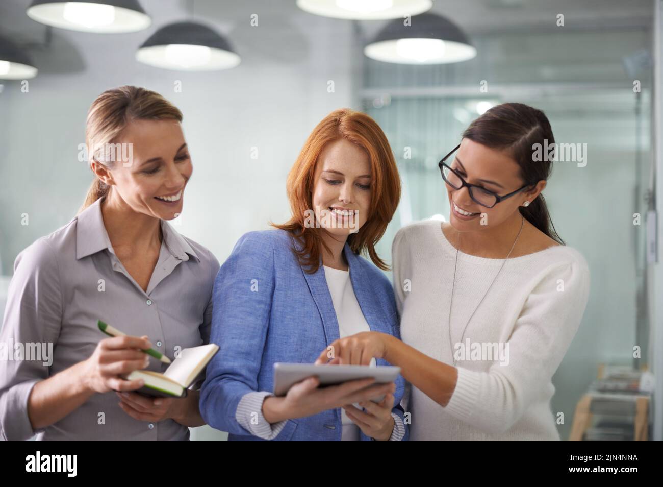 Creative team of women with tablet planning ideas, brainstorming strategy and sharing ideas in office. Manager, boss and leader asking colleagues for Stock Photo